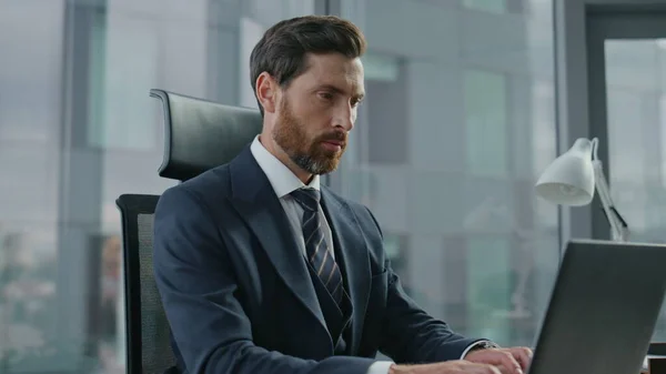 Focused bearded director finish typing on laptop shutting lid close up. Attractive serious manager thinking about business deal financial transaction profitable partnership. Busy ceo closing computer.