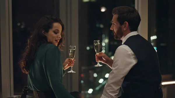 快乐的一对微笑的夫妇在全景窗前一起放松地喝着香槟 长胡子的男人抚摸着漂亮的黑发女人 情侣们在调情 度过了一个愉快的夜晚 庆祝成功 — 图库照片