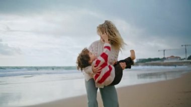 Mutlu anne okyanus sahilinde oğluyla eğleniyor. Neşeli bir aile birlikte sonbahar haftasonunun tadını çıkarıyor. Komik bebek bakıcısı, elinde kıvırcık çocukla gülüyor. Tasasız çocukluk keyfi.