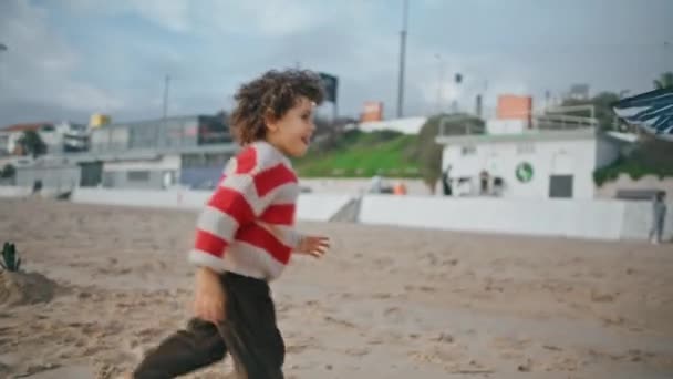 在秋天的周末 微笑的男孩在海滩上奔跑 爱玩的孩子喜欢追逐风筝玩具 可爱的学龄前儿童在家庭野餐时在多云的海岸上休息 童年幸福梦想概念 — 图库视频影像