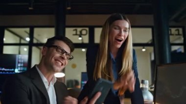 Neşeli meslektaşlar ofiste başarıyı kutluyor. Happy Traders takımı bilgisayarda başarılı borsa verilerini kontrol ediyor. İki iş adamı birlikte zaferin keyfini çıkarıyorlar.