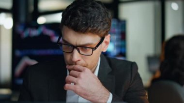 Başarılı bir tüccar ofis gecesi yakın plan. Düşünceli adam, borsa stratejisi düşünen sorunlu bir çözüm arıyor. Güvenilir girişimci komisyoncu bilgisayarla çalışıyor. Çevrimiçi yatırım satış verilerine bakıyor.