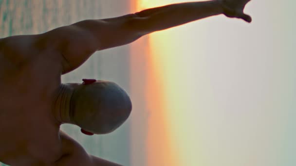 美しい夕日の中でアサナを練習ヨギシルエット 強い男は海の日の出垂直ビューで上昇手をリラックス 海で瞑想を集中未知の筋肉運動選手 ストレスフリーコンセプト — ストック動画
