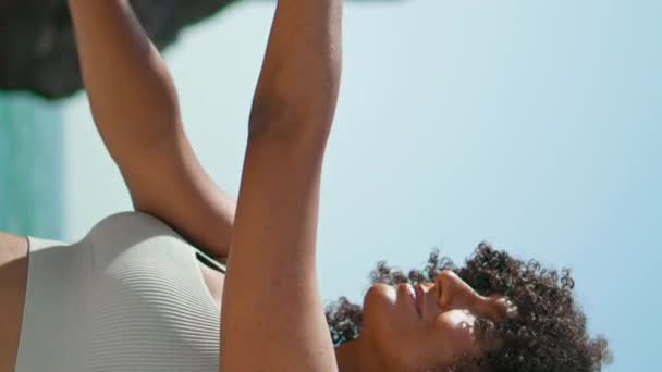 川流不息的瑜伽女孩双手交叉在前面 使伸展练习在乌尔沙海滩的垂直视图关闭 微笑着练习瑜伽的非洲裔美国女运动员 训练健康身体的妇女 — 图库视频影像