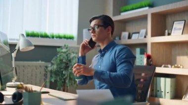 Modern ofiste kahve içen konuşan bir adam. Yakın plan ciddi iş adamı cep telefonuyla konuşuyor. İçi boş işyerlerinde içki içiyor. Bilgisayarda cep telefonuyla iletişim kuran yaratıcı serbest yazar