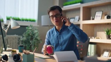 İş yerinde cep telefonuyla iletişim kuran duygusal serbest çalışan biri. Yakın plan mutlu, rahat tasarımcı akıllı telefonu arıyor ve iş arasında konuşuyor. Gülümseyen adam cep telefonu sohbetinden zevk alıyor.