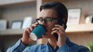 Soğuk adam kahve yudumluyor. İş yerindeki cep telefonunu arıyor. Yakın plan. Gözlüklü iş adamı telefonda konuşuyor. Ofiste keyfine bakıyor. Ciddi serbest çalışan, içki içen, sorunları tartışan biri.