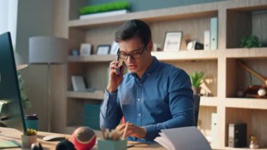 İş yerinde telefon görüşmesi yapan aktif bir adam. Yaratıcı bir acemi cep telefonunu arıyor modern ofisteki bilgisayar ekranını izliyor. Gülümseyen baş tasarımcı klavye yazıcı cevap veren arayıcı