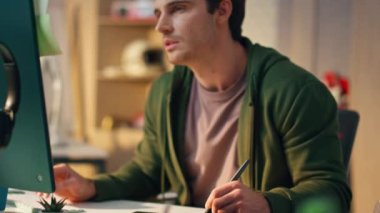 Kapanış sanatçısı, modern ofiste tablet gözleme monitörü çiziyor. Yaratıcı uzayda çalışarak tasarımı analiz eden ciddi bir adam. İşyerinde otururken odaklanmış proje tasarımcısı görünümlü bilgisayar görüntüsü