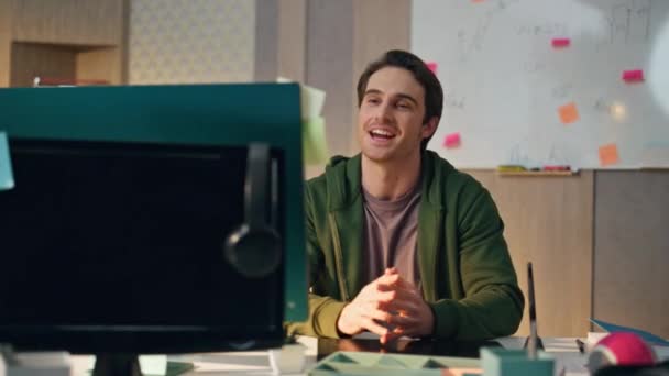 オフィスでフレンドリーなクリエイターグリーティングコンピュータビデオコール 職場で手を見てモニター画面を振って幸せな笑顔の男を閉じます デスクトップ仮想コールを持つ陽気な男デザイナー開くノートブック — ストック動画