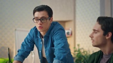 Gayri resmi ofiste projeyi tartışan yaratıcı iş adamları. İki adam birbiriyle konuşan bilgisayar ekranına bakıyor. Gözlüklü adam iş yerindeki meslektaşıyla konuşuyor. Takım çalışması konsepti