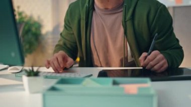 Ofiste çalışan odaklı tasarımcı bilgisayarı yakın plan. Profesyonel yaratıcı eller evde klavye yazarken tablet çiziyor. Stylus kullanan genç bir sanatçı uzak bir iş yerinde kendi tasarımını yaratıyor. 