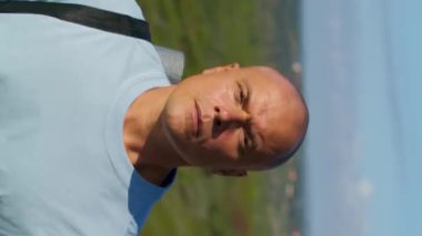 Atletik adam yoga minderiyle dışarıda yürüyor. Yaz güneşinde doğal parka giden turist videosu. Temiz hava alan cesur adam..