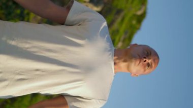 Yeşil dağda yoga pozisyonunda nefes alan bir sporcu. Odaklanmış adam, namaste jesti yapıyor, gün ışığında dinleniyor. Yakışıklı kaslı adam tek başına dikey olarak dinleniyor. Huzurlu ruh hali dengesi.