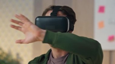 Ofiste yeni başlayanlar için meta-evren araştırması. Görünmez arayüze dokunan akıllı VR gözlüklü adam yeni 3D oyunu test ediyor. Sanal simülasyon kulaklık kullanan sakin yaratıcı gelecekteki verileri daldırıyor