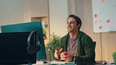 Mutlu adam video görüşmesini selamlıyor. Ofisteki meslektaşını takdim ediyor. Yakın çekim. El sallayan iki adam birlikte monitör ekranına bakıyor. Arkadaş canlısı ekip masadaki iş ortaklarıyla video görüşmesi yapıyor.
