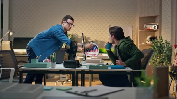 オフィスでカラーウォッチを議論する若いクリエイター コンピュータテーブルでブレインストーミングするプロフェッショナルを設計します 机の上に立っている男性が同僚にサンプルを見せます 選択のポイントを作る男 — ストック動画