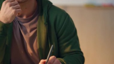 Yakın plan ışık ofisindeki bilgisayarda çalışan odaklı adam. Mutlu neşeli yaratıcı cep telefonuna cevap veriyor ve kapalı alanda tablet çiziyor. İş yerinde cep telefonu aramasından keyif alan çizimler yapan tasarım uzmanı 