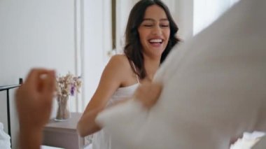 Şakacı aşıklar yatak odasında eğleniyorlar. Pencerenin iç tarafında yastıkla erkek arkadaşına vuran komik bir kadın. Pijamalı çift evde yastık savaşı yapıyor. Rahatlamış yeni evliler sabahlarını