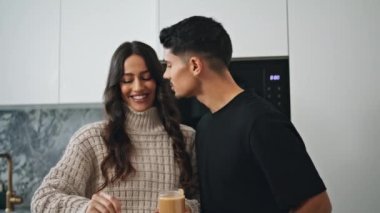 Gülümseyen aşıklar sabah mutfağında öpüşüyorlar. Mutlu çift evde birlikte yemek pişiriyor. Seksi eşler modern iç güzelliklere gülüyorlar. Sevilen adam ve kadın rahat bir evde fıstık ezmesiyle eğleniyorlar. 