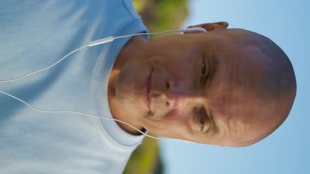 快乐的男人听耳机音乐特写 放松运动员享受高山度假使用耳机在美丽的风景 适合做运动后休息的人 积极的早晨生活方式 — 图库视频影像
