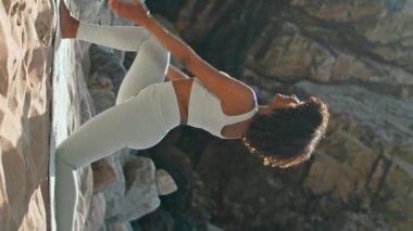 Esnek kadın düşük hamlede poz veriyor kayalık kumsalda güneşli bir sabah dikey olarak. Genç yogi kızı, Hilal Ay 'ı, minder eğitimine göre asana yapıyor. Esmer kadın yoga savaşçısı pozu veriyor.