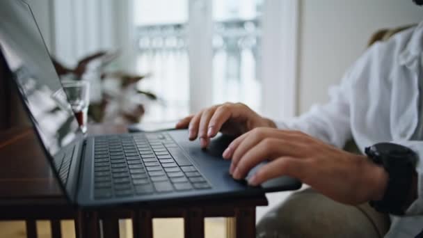 アパートのクローズアップでキーボードのラップトップを入力する男の手 自宅のオフィスでコンピュータボタンを押すカジュアルスタイルの男指 遠隔職場で単独で作業する現代的なデバイスを使用した未知のフリーランサー — ストック動画