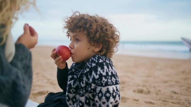 해변에서 피크닉을 소년입니다 즐거운 아이가 모르는 보모와 과일을 먹습니다 걱정없는 — 비디오