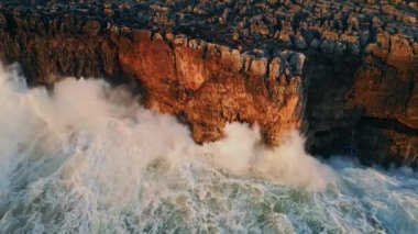 Dev okyanuslar çok yavaş çekimde yüksek tehlikeli kayalara çarpıyor. Havadan gelen güçlü dalgalar yüksek sahil kayalıklarına vurarak beyaz köpük oluşturuyor. Nefes kesen dalgalı deniz taşlara sıçrıyor..