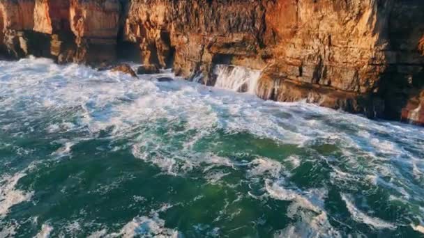 ドローンは強力な海の波を吹き飛ばす泡で沿岸の岩で破壊した 海岸の崖に衝突する嵐の泡立つ海水は スプラッシュスーパースローモーションを作ります 息をのむような海洋景観 — ストック動画