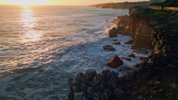 岩の海岸の空の景色を洗う海の波の泡立つ驚くべき夕日空 海面を映した黄金の夜の日差し 火山沿岸の崖のゆっくりとした動きで破裂する嵐の水 — ストック動画