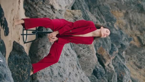 Расслабленная Женщина Позирует Пляжных Скалах Элегантный Красный Костюм Облачный День — стоковое видео