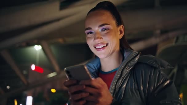 Uśmiechnięta Dziewczyna Szuka Smartfona Ekran Stojąc Godzinach Wieczornych Zbliżenie Miasta — Wideo stockowe