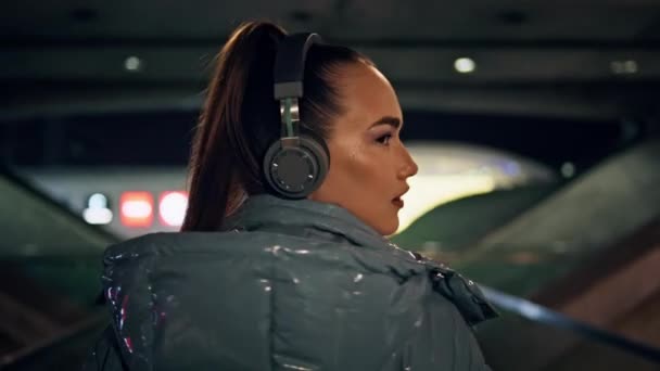 Bright Playful Girl Walking Dark Subway Wearing Modern Wireless Headphones — Stock Video