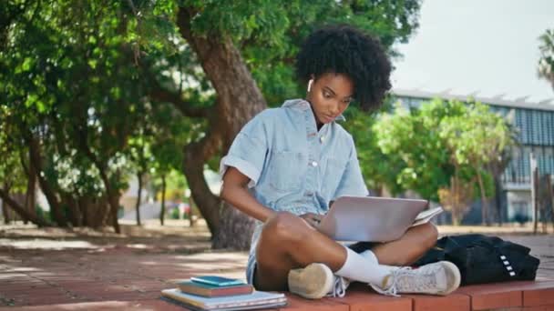 卷曲少年在线学习与笔记本电脑坐在阳光灿烂的街道 忙碌的非洲裔美国女孩在网上搜索信息 做笔记 聪明的年轻女子在户外电脑屏幕上写概要 — 图库视频影像