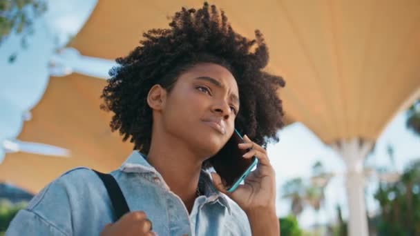 黑色头发的女孩打电话给手机走在夏日街上特写 卷曲的非洲裔美国少女在讲智能手机时不满意的谈话 不高兴的年轻女子一边散步一边说着话 — 图库视频影像