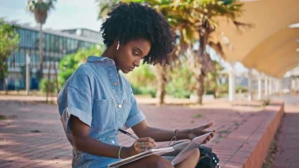 Κορίτσι Μαθαίνουν Online Μαθήματα Κρατώντας Σημειώσεις Copybook Κάθεται Ηλιόλουστο Δρόμο — Αρχείο Βίντεο