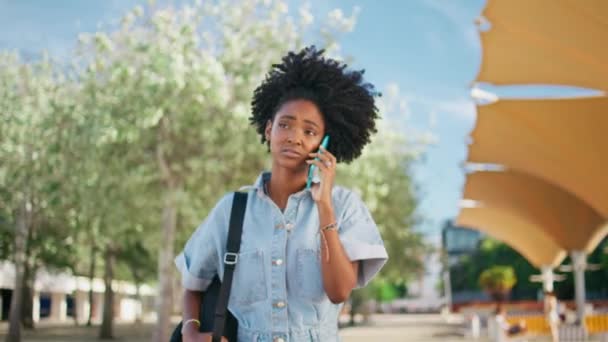 非洲女孩抱怨手机走在美丽的城市街道近旁 年轻的卷曲女人不满意的电话 感觉压力正在消失 可悲的青少年在智能手机的对话中争吵 — 图库视频影像