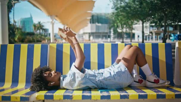 Девушка Колледжа Держит Учебник Лежащий Красочной Скамейке Улиц Стильный Африканский — стоковое видео