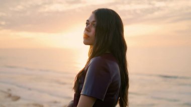 Portrait of romantic woman at amazing sunset sky. Dreamy attractive model posing in front picturesque ocean holding book close up. Long-haired tranquil girl looking on beautiful seascape. Concept rest