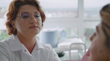 Profesyonel kozmetik uzmanı, yüz işlemleri hakkında bilinmeyen kadınlara danışmanlık yapıyor. Kadın dermatolog, yüz gerdirme ameliyatından önce cilt durumunu incelemek için hastanın yüzüne dokunuyor.