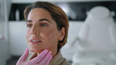 Bilinmeyen güzellik uzmanı, lüks kozmetoloji kliniğinde oturan çekici kadını kontrol ediyor. Doktor yüz muayenesinde müşterinin yüzüne dokunan eldivenler verdi. Güzellik salonu prosedür kavramı.
