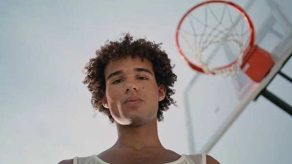 篮球运动员摆上街头肖像画 在城市操场的特写训练后 年轻人面对着休息 卷曲运动员看相机与橙色球的低角度 有信心的家伙在体育场笑 — 图库照片