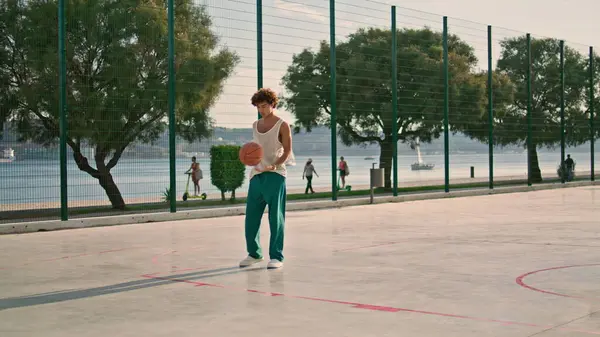 一个骨瘦如柴的人独自练习街头篮球 专注于非洲发型的家伙试图在体育场进球 认真的街头足球运动员在城市操场上训练 夏季生活方式 — 图库照片