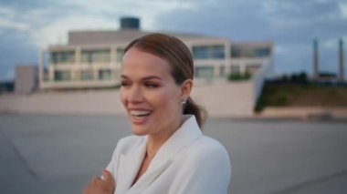 Zarif beyaz takım elbiseli bir kız sokakta gülüyor. Güzel bir iş kadınının portresi soğuk bulutlu bir hafta sonunda geziniyor. Güzel bayan kaygısız gezintilerin tadını çıkarıyor..