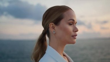 Deniz günbatımını hayranlıkla seyreden muhteşem bir iş kadını kıyıda tek başına dikiliyor. Akşam deniz manzarasına bakan çekici ve başarılı bir kadın. Güzel bayan sakin okyanus günbatımını seyrediyor. Dışarıda dinleniyor.