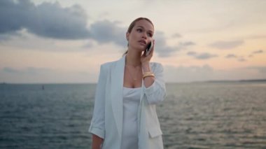 İş kadını deniz batımında akıllı telefonuyla konuşuyor. Beyaz şık bir takım elbise giyiyor. Kendine güveni tam ciddi bir kadın, gün batımını bekleyen güzel gökyüzünde tek başına telefon konuşmasını bitiriyor. Meşgul kadın dışarıda takılıyor..