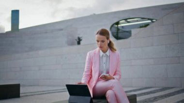 Şirket çalışanı online konferans düzenliyor. Kenar mahallelerde dizüstü bilgisayarla oturuyor. Açık hava görüntülü konuşma yapan zarif bir profesyonel yönetici. Kulaklık takan serbest çalışan kız projeyi tartışıyor..