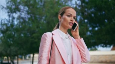 Akıllı telefonda konuşan şirket çalışanı Green City Caddesi 'ni kapatıyor. Açık havada rahatça dolaşırken telefonla konuşan zengin çekici bir iş kadını. Zarif ve çekici bir bayan telefonla haberleri paylaşıyor..
