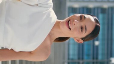 Kız blogcu, güneşli caddede dikey beyaz kıyafetlerle dikey olarak duran video içeriğini kaydediyor. Güzel, şık bir kadın telefonda konuşuyor. Web kamerasından kahve fincanı gösteriyor. Esmer video çağrısı
